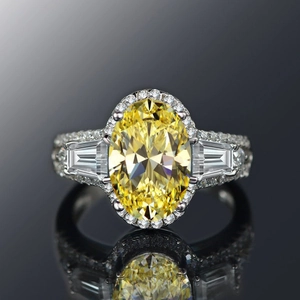 Detailopname van luxe ring met ovale gele edelsteen en diamanthalo op witgouden band