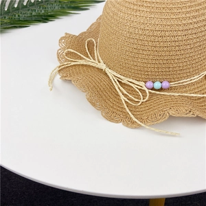 Detailed view of woven straw hat featuring a bow and colorful beads for girls