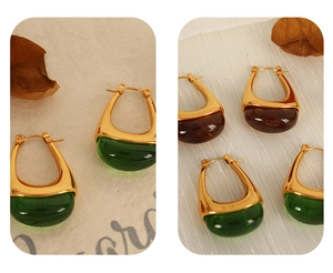 Detail of teardrop earrings with emerald and amber gemstones in gold U-shaped frames