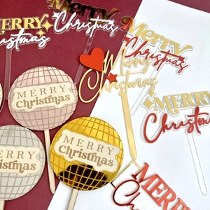 Detail of assorted gold and red acrylic Merry Christmas cake toppers for party decor