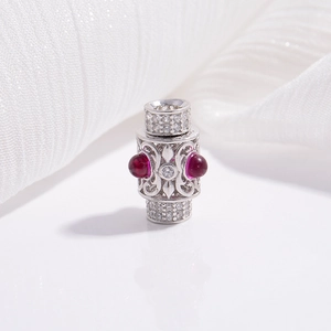 Macro shot of silver hollow barrel bead with red gemstones and zircon flower pattern