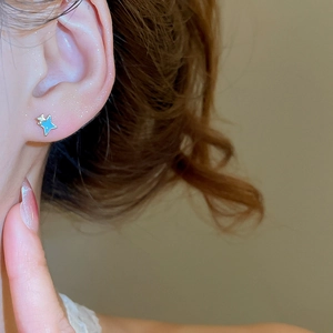 Gros plan d'une boucle d'oreille étoile en émail bleu portée avec accents métalliques