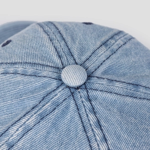 Detailed macro view of light blue denim fabric texture and stitching on baseball cap