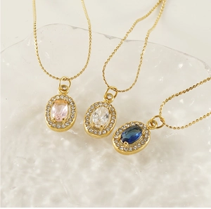 Detailed macro view of three gold-plated necklaces with pink, white, and blue zircon pendants