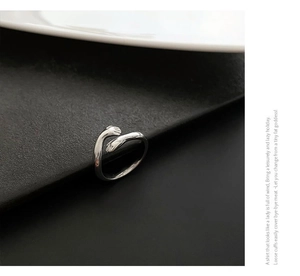 Detailopname van een zilveren ring met knuffelende handen op zwarte textuur