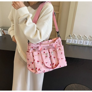 Detailed view of pink tote bag with red cherry print and adjustable shoulder straps