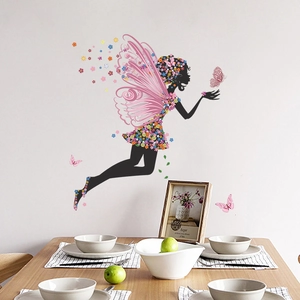 Détail du sticker mural fée avec ailes roses et robe florale sur un mur de salon gris