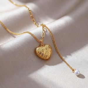 Gros plan d'un pendentif cœur doré texturé avec perle sur un tissu en soie élégant