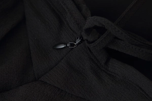 Close-up of invisible back zipper on black ruffle dress with textured crepe fabric
