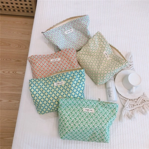 Floral cotton makeup bags with zippers and simple wish labels on striped linen background