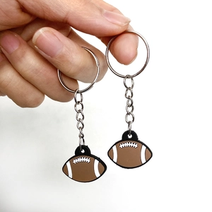 Detailed view of a brown rugby ball keychain with white stitching and silver metal ring