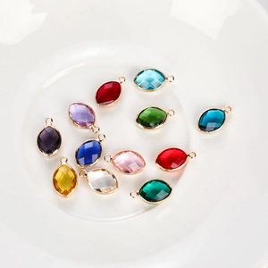 Colorful marquise cut glass pendants with gold metal frames on a ceramic plate