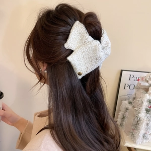 Elegant tweed hair claw with gold button detail shown on a model from the back view