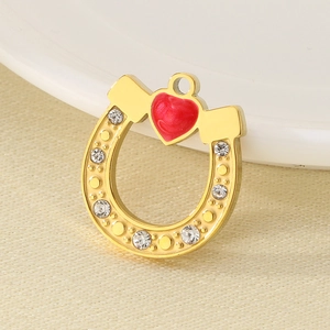 Detailed macro view of a golden horseshoe pendant with red enamel heart and clear rhinestones