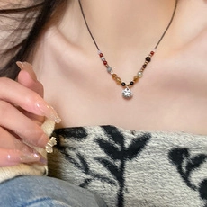 Close-up of a multi-color beaded necklace with a sparkling cubic zirconia pendant on neck
