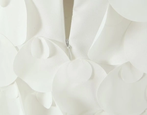 Vista macro dell'abito bianco con petali 3D e chiusura con zip invisibile sul retro