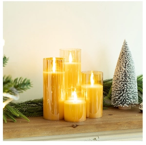 Close-up of four amber glass LED pillar candles with warm flame on a wooden mantel