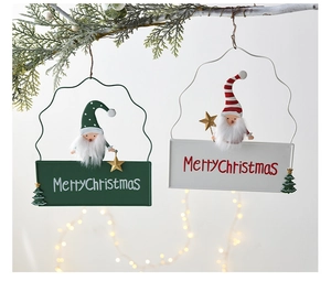 Close-up of Merry Christmas metal signs with plush gnomes hanging on pine branches