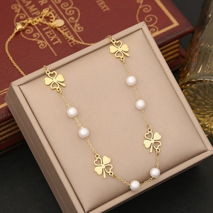 Detail of gold layered necklace featuring heart clover charms and white pearls on jewelry box