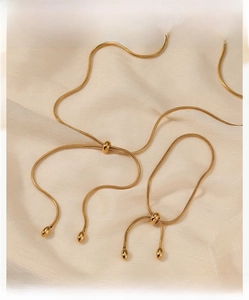 Detail of adjustable gold snake chain jewelry set on elegant cream satin fabric
