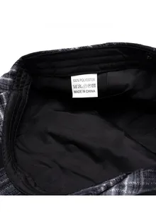 Detailed macro view of the interior lining and care label of the plaid newsboy cap