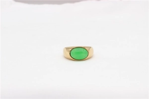 Detailed macro view of an oval green gemstone set in a wide gold plated stainless steel ring