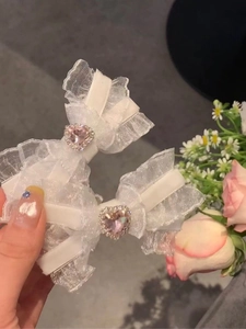 Macro view of white lace bow hair clips with pink heart-shaped crystal gemstones
