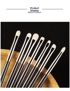 Detail of 8 eye makeup brushes with soft bristles and silver ferrules on wooden tray