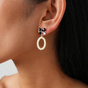 Elegant black bow earrings with white pearl oval drop pendant shown on model side profile