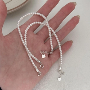 Detail of S925 sterling silver heart charm and lustrous white pearls on hand