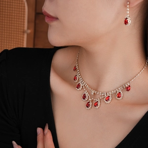 Close-up of model wearing luxury gold necklace and earrings with red teardrop stones