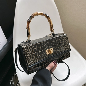 Detail of black crocodile texture handbag with signature bamboo handle and twist lock