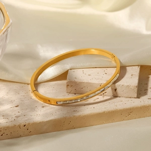 Primer plano detallado de un brazalete de acero inoxidable dorado con circonitas