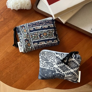 Detail of two boho linen coin purses with floral and geometric patterns on wood surface