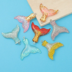 Close-up of colorful resin mermaid tail charms with sparkling glitter and metal loops