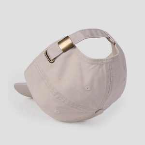 Detail of adjustable metal brass buckle and cotton fabric texture on beige baseball cap