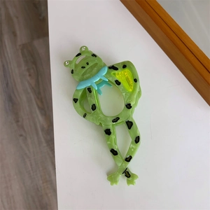 Detail der grünen Frosch-Haarklammer aus Acetat mit Strass-Augen und blauem Dekor