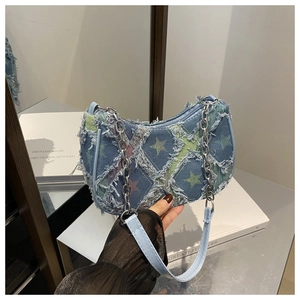 Detail of blue denim shoulder bag featuring star patterns and raw fringe edges
