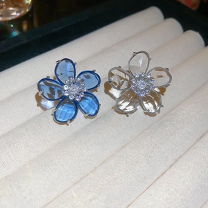 Macro shot of blue and clear crystal flower ear cuffs with silver-tone floral petals