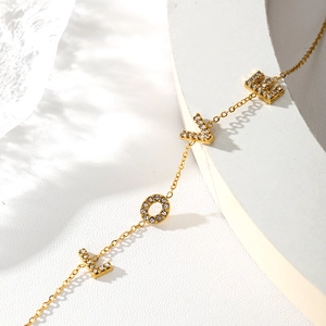 Close-up of gold-plated LOVE bracelet with sparkling cubic zirconia on a white surface