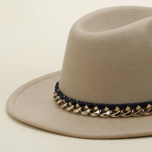 Close-up of khaki wool felt hat featuring a gold chain and navy braided ribbon detail