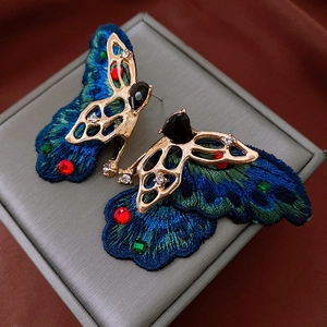 Detailed macro of vintage butterfly earrings with gradient embroidery and gemstones