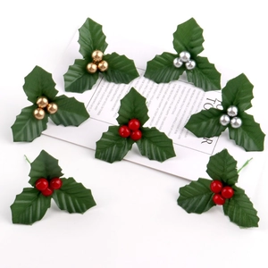 Artificial Christmas Holly Leaves and Berries in Red Gold Silver Colors on White Surface