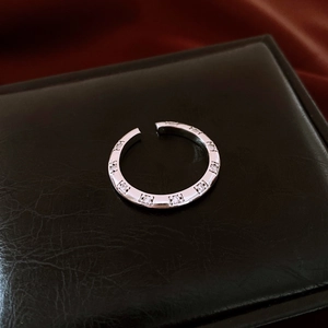 Macro detail of silver ring with inlaid cubic zirconia stones on textured black background