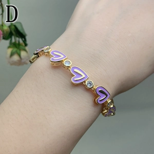 Macro detail of gold bracelet featuring purple enamel hearts and sparkling zircon stones