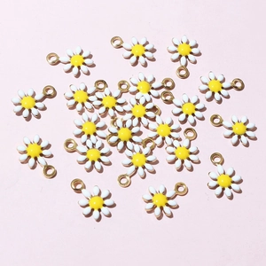 Flat lay macro of small white and yellow daisy flower pendants for DIY jewelry making