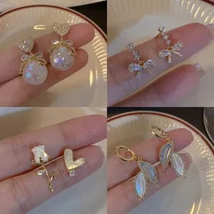 Detailed showcase of four elegant pearl earrings featuring heart and bow motifs