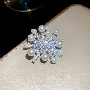 Elegant snowflake brooch with cubic zirconia and pearls on silver metal base