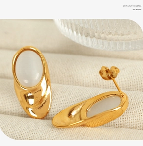 Detail view of 18k gold plated titanium steel earrings with white oval opal stones