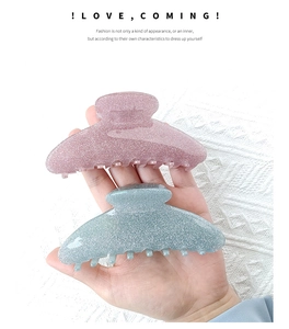 Detail showing two glitter acrylic shark hair clips in pink and teal colors